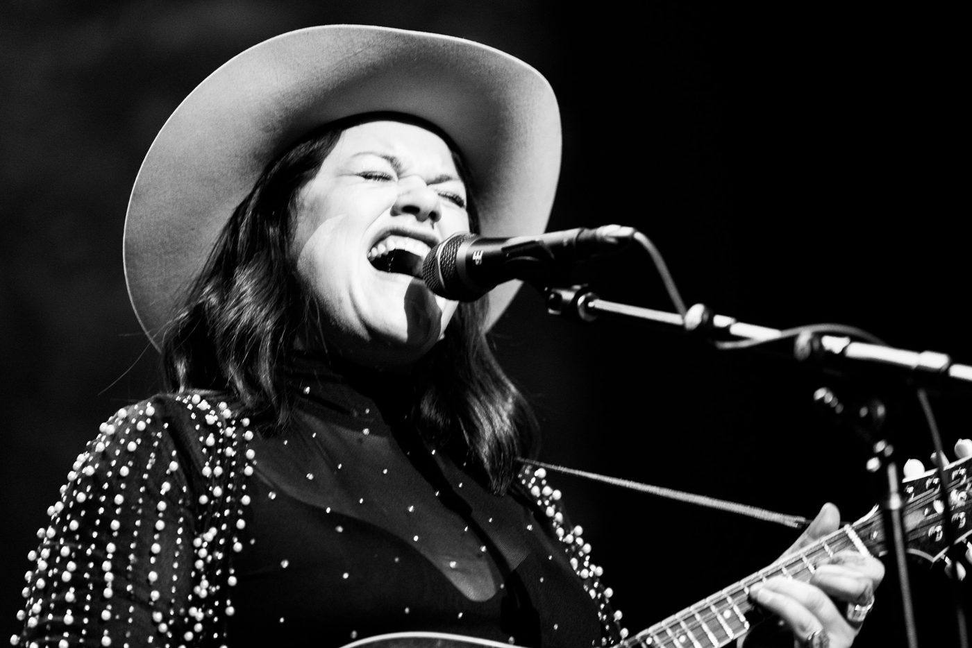 Mattie Schell in a cowboy hat singing into the microphone
