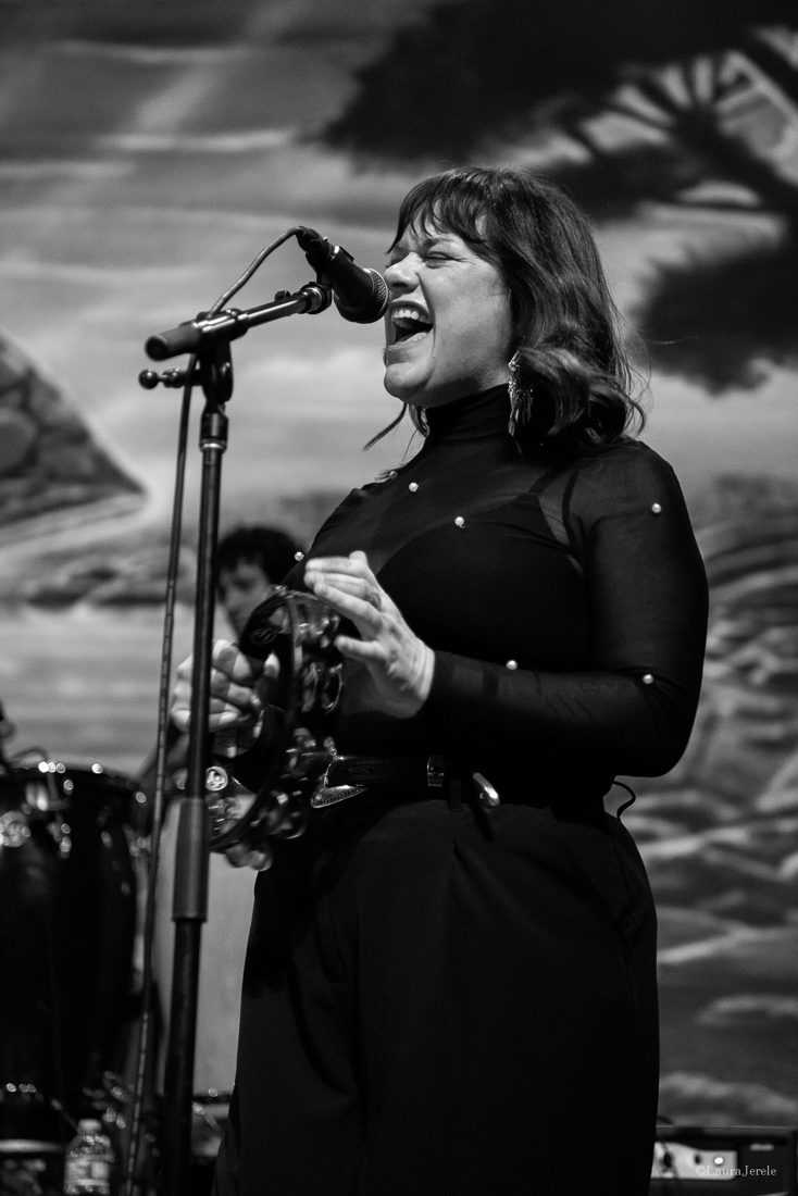 Mattie Schell singing on stage with a tambourine